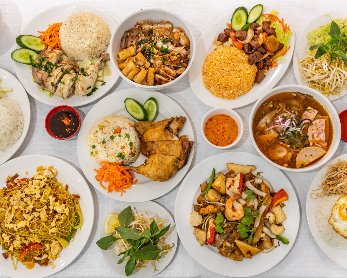 A table of Pho N Rolls dishes: pho, broken rice, Hainanese chicken, stir-fried noodles and more